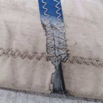 UV-degraded sailcloth and frayed stitching, showing brittleness and wear.