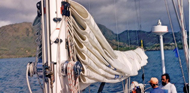 A mainsail flaked neatly on the boom with vertical Dutchman control lines guiding the folds
