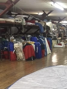 Loft shelves organized with colorful sail bags for safe, dry off-season sail storage indoors.